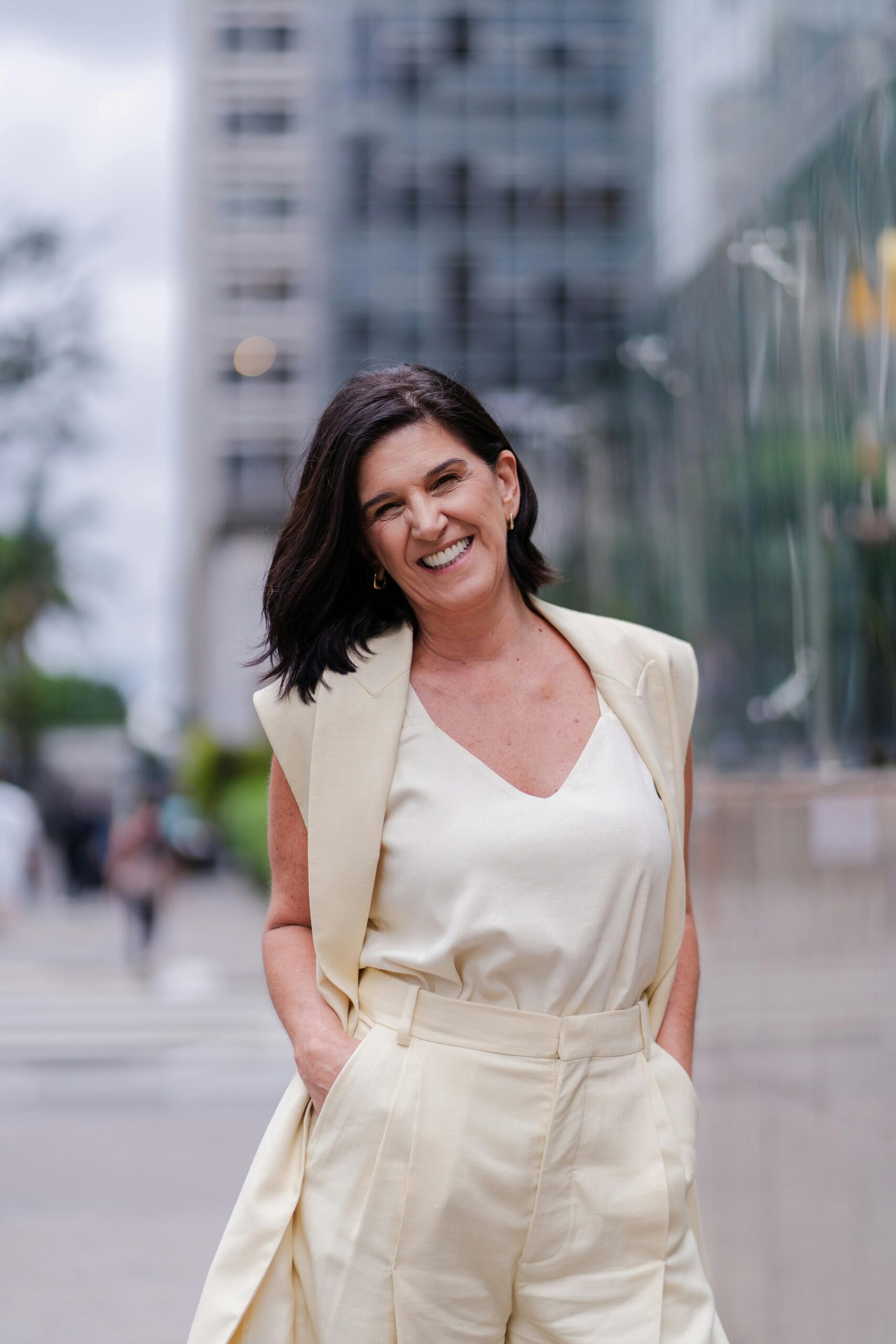 Smiling woman in a cream outfit posing confidently in a city street.